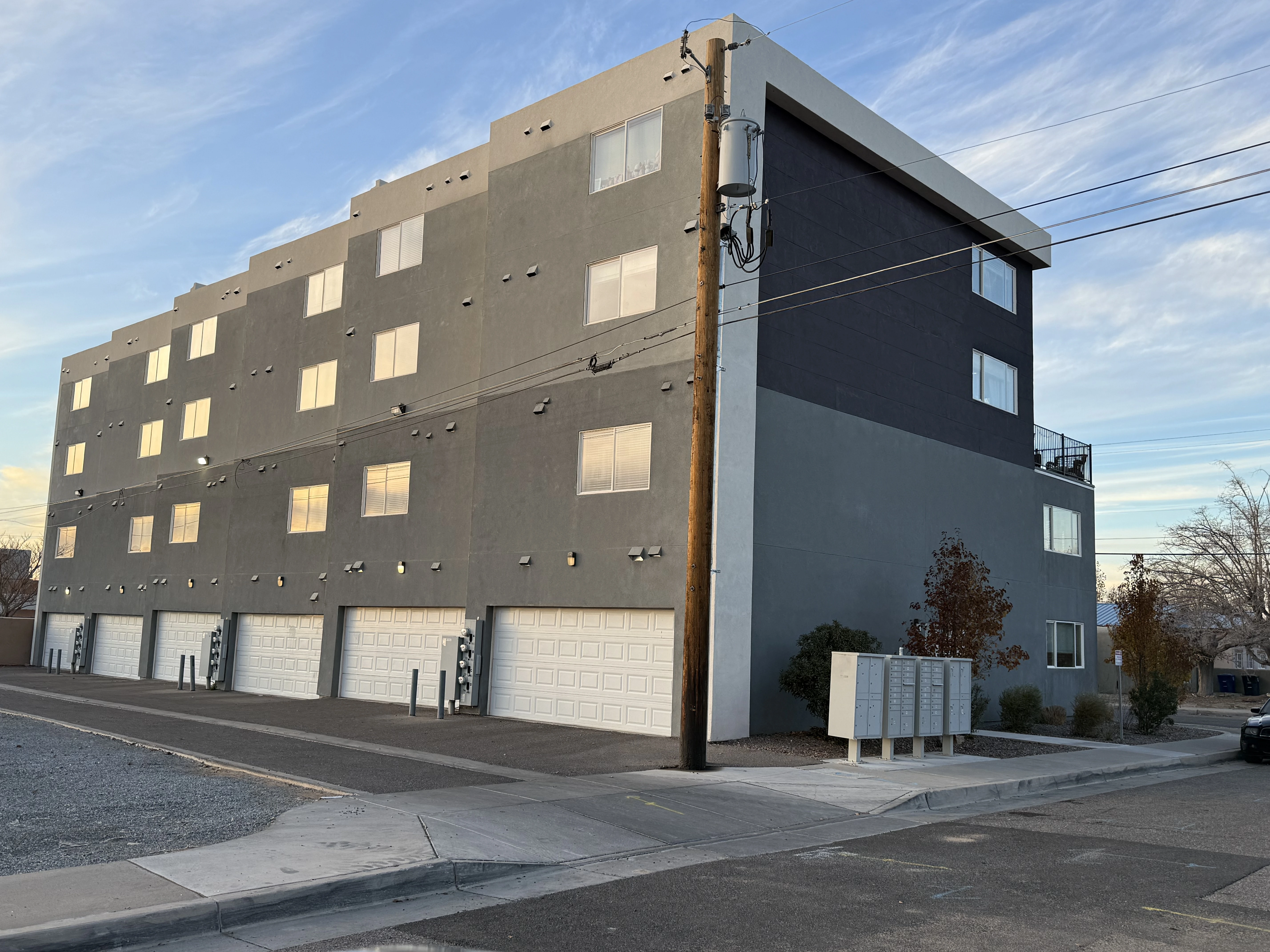 A gray apartment building featuring two garages at its base, showcasing a modern architectural design.